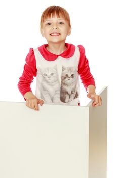 A nice little girl is looking because of an empty banner in which you can insert any text. The concept of a happy childhood, advertising, selling goods. Isolated on white background.