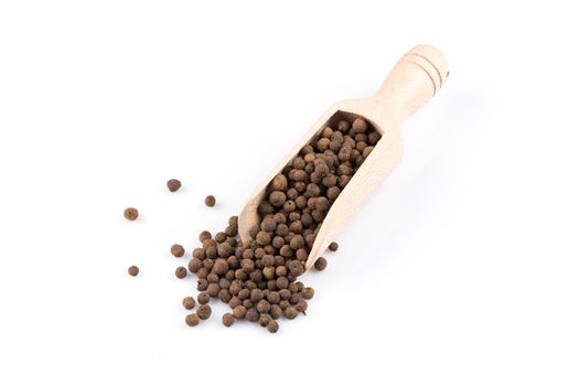 Wooden shovel with large black peppercorn scattered from it