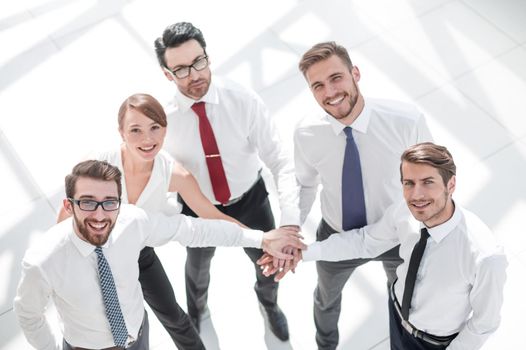 young employees standing in a circle and folding their hands together. photo with copy space