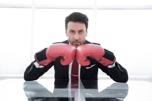 serious businessman in Boxing gloves sitting at his Desk.photo with copy space
