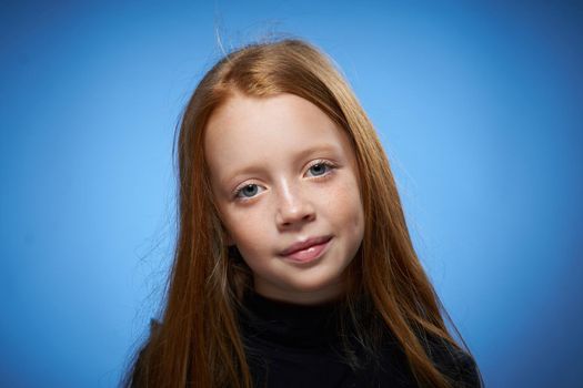 redhead girl with freckles on her face posing close-up blue background. High quality photo