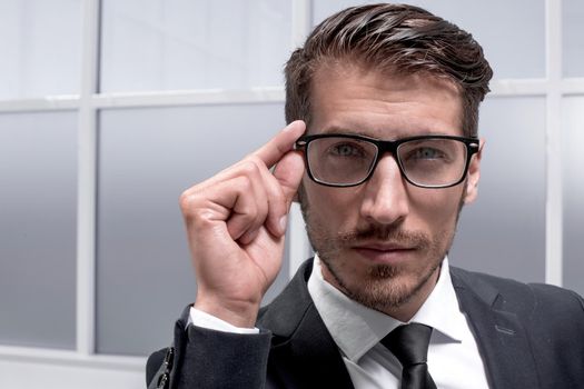 young successful businessman with a serious face stands in the office in a business suit