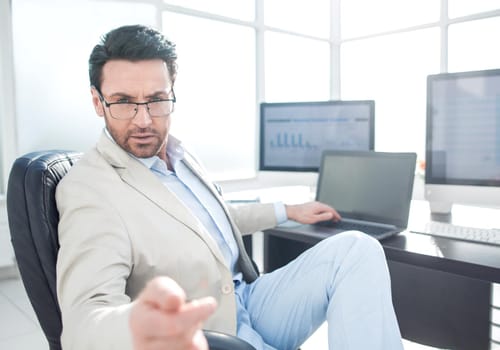businessman sitting at his Desk and pointing at you.photo with copy space