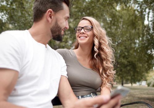 young couple sitting on a bench in a city Park.people and technology