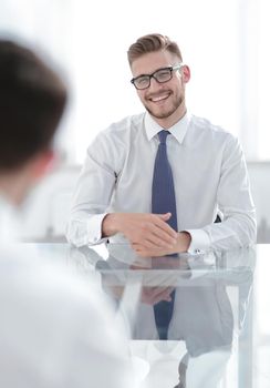 Manager talks to the employee sitting at his Desk.business concept