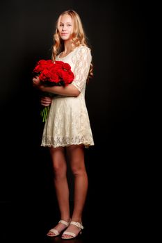 Beautiful young teen girl with a bouquet of flowers. Studio photo on a black background. The concept of style and fashion.