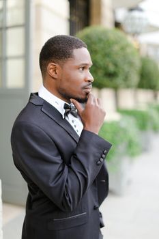 Afro american happy good looking man wearing suit and standing outside. Concept of black businessman.