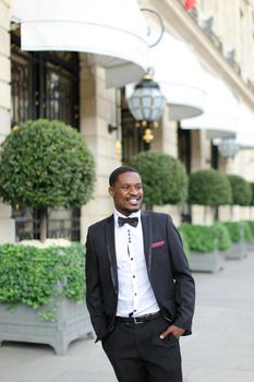 Afro american smiling man wearing suit and standing outside. Concept of black businessman.