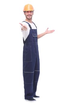 in full growth. smiling man in overalls pointing somewhere up. isolated on white background