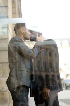 Reflection in window of two happy kissing boys, afro american and caucasian. Concept of gays and lgbt.