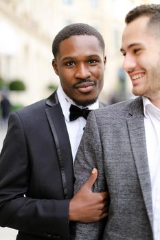 Focus on fro american handsome man hugging european boy wearing suit. Concept of gays and same sex couple.