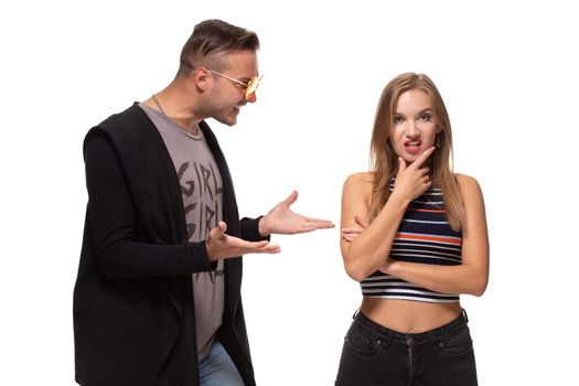 Young emotional man and woman quarrel. Man screaming at the woman waving her arms on white background