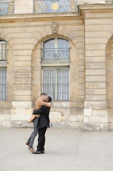 Afro american man holding caucasian guy and waling in building background. Concept of gays and same sex couple.