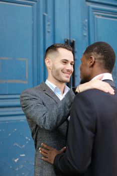 Caucasian man hugging afro american guy in door background. Concept of lgbt, gays and same sex couple.