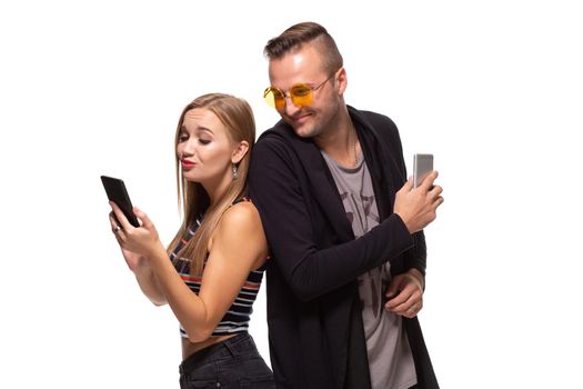 Man and woman stand with their backs to each other with telephones in their hands on white background. Studio shot