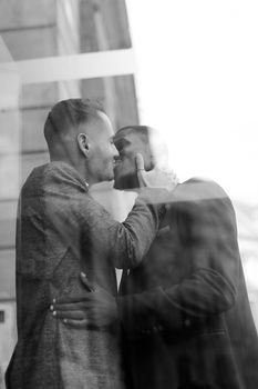 RBlack and white reflection in window of two kissing boys, afro american and caucasian. Concept of gays and lgbt.