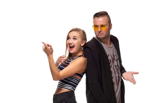 Portrait of the happy couple looking and pointing into the distance, isolated on white background. Emotional young couple laughing at something