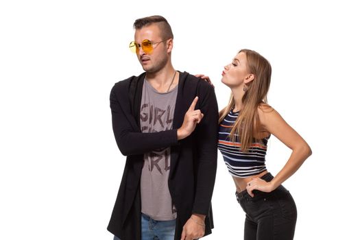 Young woman trying to kiss a young man. Isolated on white background. Studio shot