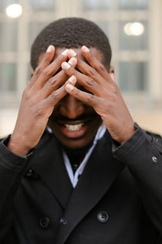 Portrait of afro american boy, closed eyes with hands. Concept of positive emotions.