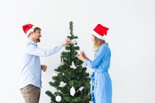 Holidays and festive concept - Young family couple decorating the christmas tree.