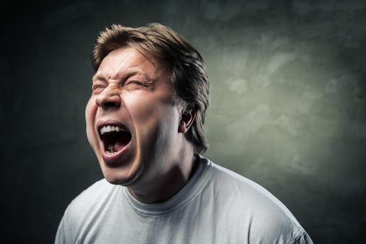 portrait of young angry man over dark grey background