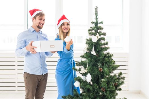 Holidays and festive concept - Young family couple decorating the christmas tree.