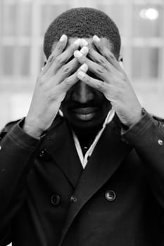 Black and white portrait of afro american boy, closed eyes with hands. Concept of sad emotions and problems.