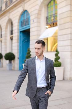 Young caucasian nice man walking in city and wearing grey suit. Concept of fashion and businessman.