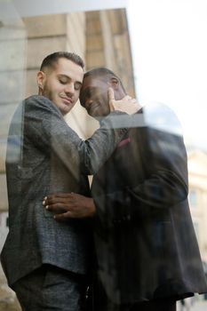 Reflection in window of two hugging men, afro american and caucasian. Concept of gays and lgbt.