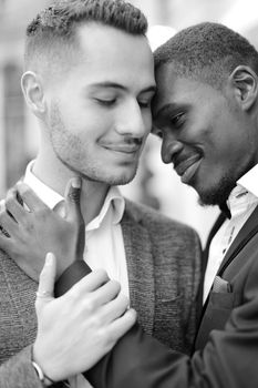 Black and white portrait of afro american gay hugging caucasian boy, wearing suits. Concept of lgbt and same sex couple.