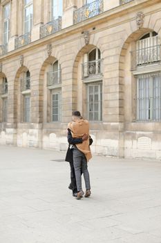 Afro american man holding caucasian male person and waling in building background. Concept of gays and same sex couple.