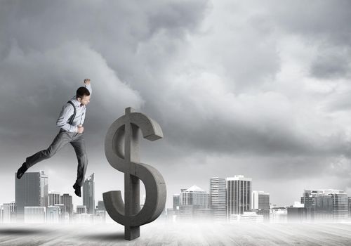 Young furious businessman going to crash with fist stone dollar symbol