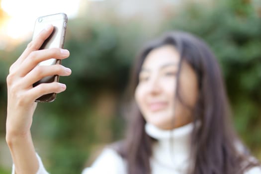 Focus on smartphone, blurred asian woman making selfie. Concept of modern technology.