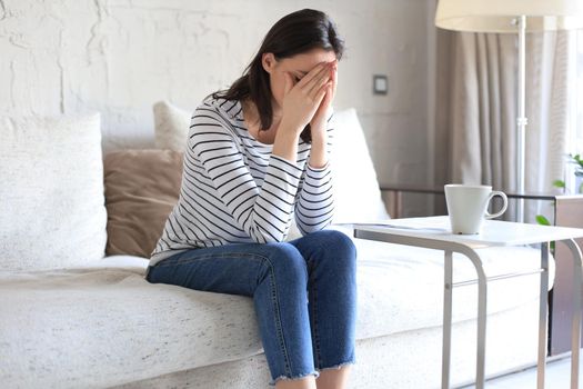 Sad woman sitting on a sofa in the living room