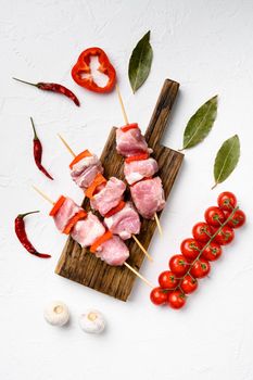 Kebabs raw meat and vegetables on skewers set, top view flat lay, on white stone table background