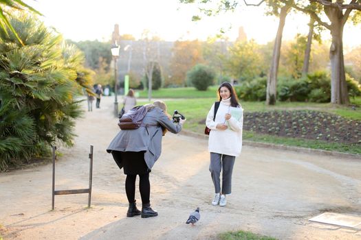 Photographer taking photo of chinese girl with documents outdoors. Concept of asian student.