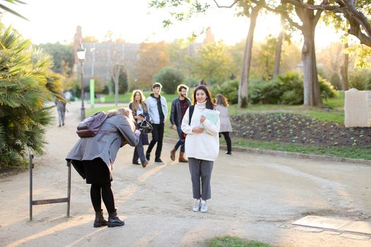 Photographer taking photo of chinese girl with documents outside. Concept of asian student.