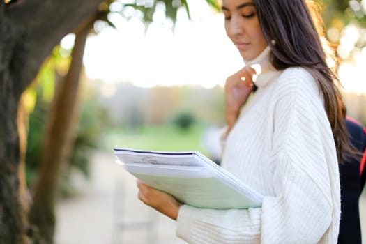 Focus on documents in korean girl hands outdoors. Concept of asian student.