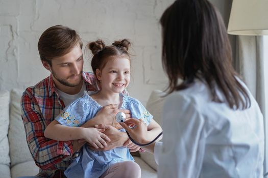 Little girl at the doctor for a checkup. Doctor woman auscultate the heartbeat of the child