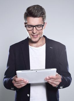 young man holding a tablet in his hands, looking at something and smiling