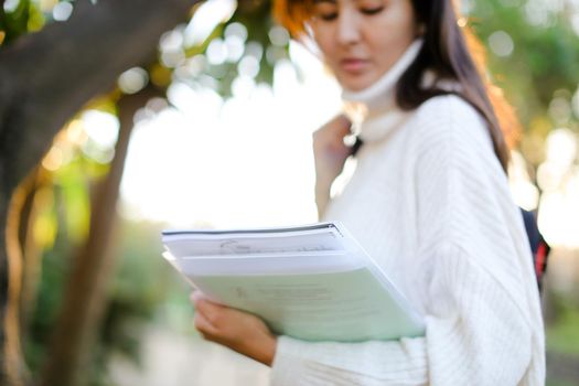 Focus on documents in japanese girl hands outdoors. Concept of asian student.