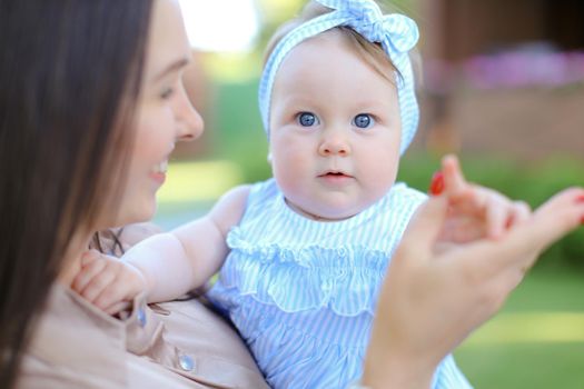 Closeup young european mother holding little female child in blue dress. Concept of motherhood and child.