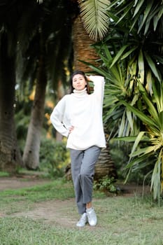 Korean girl walking in tropical park and standing near palms. Concept asian beauty and nature.