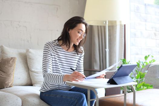 Smiling girl sit on couch watching webinar on laptop. Happy young woman study on online distant course