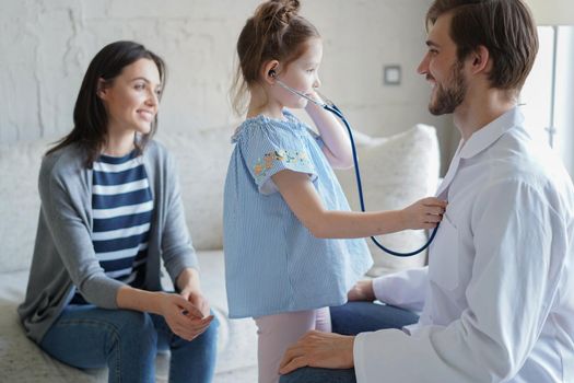 Little girl at the doctor for a checkup. Doctor woman auscultate the heartbeat of the child