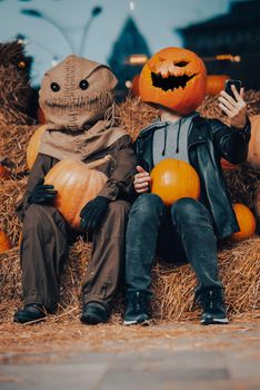 A guy with a pumpkin head sits next to a scarecrow. Halloween Concept