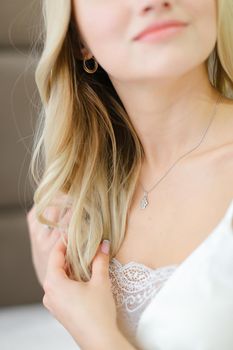 Close up lips of blonde bride wearing white clothes. Concept of human beauty and tender light lipstick.