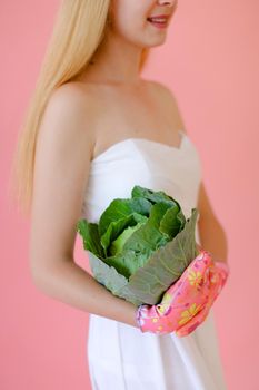 Caucasian woman keeping cabbage in pink monophonic background. Concept of harvest and photo session at studio.