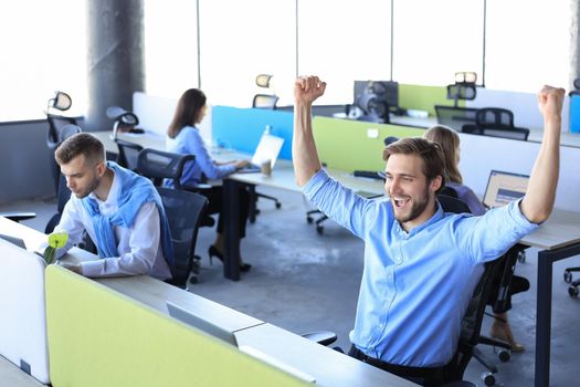 Businessman with arms raised celebrating success recived good news on e-mail in office