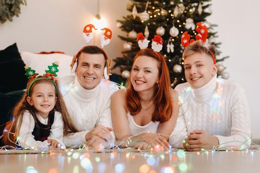 Close-up portrait of a happy family lying near a Christmas tree celebrating a holiday.